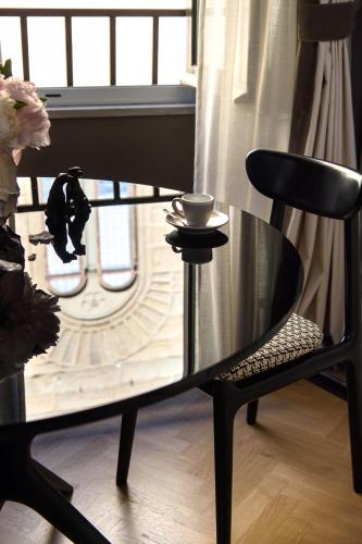 a glass table and a chair with a cup on it at Tornabuoni Suites Collection Residenza D'Epoca in Florence