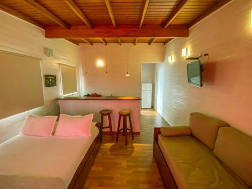 a room with a bed and a couch and a bar at El Diablo y el Mar in Punta Del Diablo