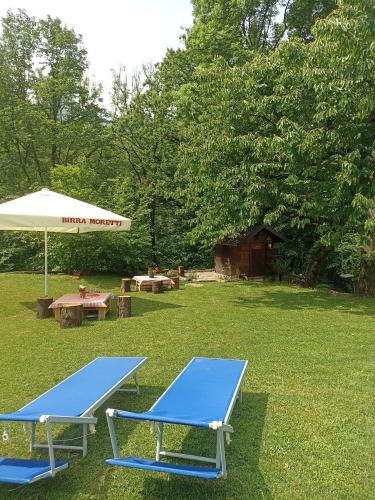 two blue picnic tables and an umbrella in a yard at Baita Eleonora in Argegno
