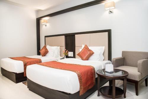 a hotel room with two beds and a chair at Hotel Platinum Shravasti in Katra