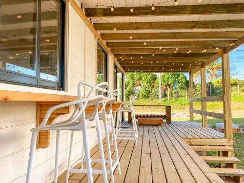 a deck with two chairs and a table and a bench at El Diablo y el Mar in Punta Del Diablo