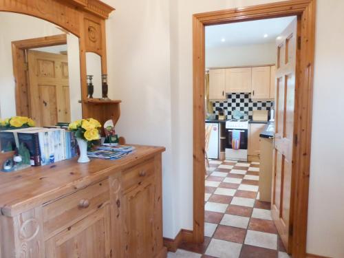 uma cozinha com um armário de madeira e um piso de xadrez em Borahard Lodge em Newbridge