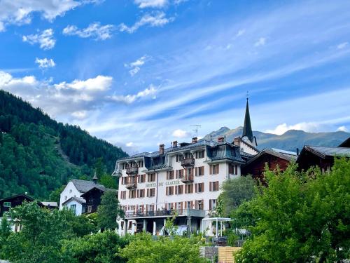 a large white building in a village with a church at DU GLACIER Boutique & Traditions Hotel in Fiesch