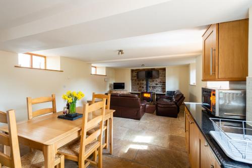 a kitchen and living room with a wooden table and chairs at Chapel Beck, Millthrop in Sedbergh