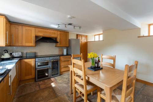 a kitchen with wooden cabinets and a wooden table at Chapel Beck, Millthrop in Sedbergh