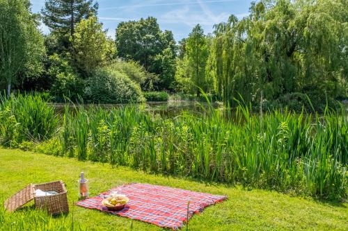 a picnic table in the grass next to a pond at Charming cottage in beautiful countryside with a boating lake - The Calf Pens in Ipswich