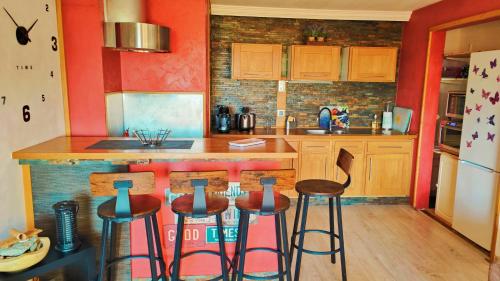 - une cuisine avec des murs rouges et des tabourets de bar dans l'établissement Piscine chauffée à débordement Au Cap de L'Esterel ! Entre Théoule et Saint-Raphaël, au Trayas
