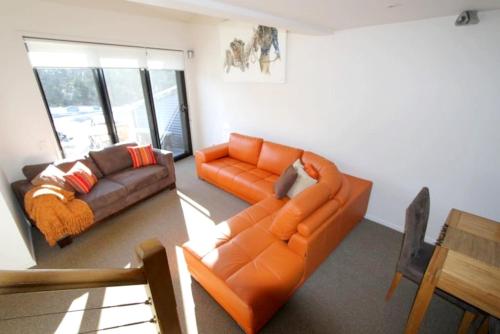 a living room with an orange couch and a table at Angala 1 Lovely Woodridge 2-Bedroom Apartment in Thredbo