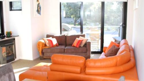 an orange couch in a living room with a couch and a fireplace at Angala 1 Lovely Woodridge 2-Bedroom Apartment in Thredbo