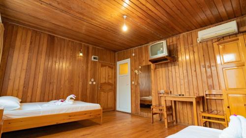 a room with a bed and a tv on a wooden wall at Turkmen Tree Houses in Olympos
