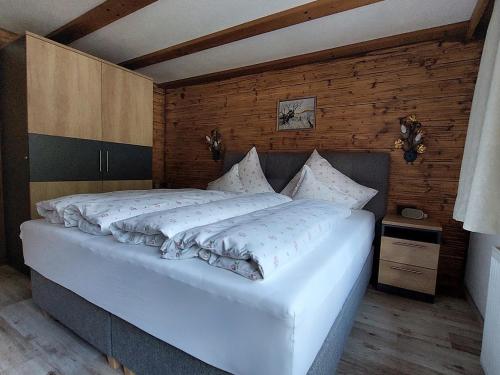 Gästehaus Rita في سانكت أنتون ام ارلبرغ: سرير أبيض كبير في غرفة بجدران خشبية