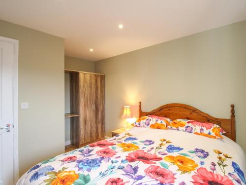 a bedroom with a large bed with a floral bedspread at Roundham Cottage in West Bay