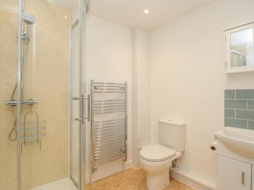 a bathroom with a toilet and a glass shower at Roundham Cottage in West Bay