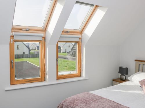 a bedroom with two windows and a bed at C64 Cahermore Holiday Village in Enniscrone