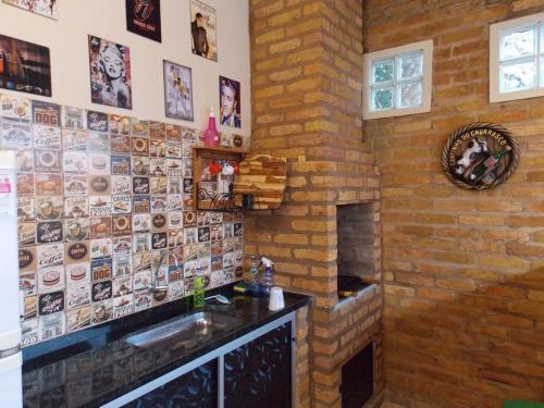 a kitchen with a sink and a brick wall at Chalé Paraíso com piscina privativa em Brotas SP in Brotas