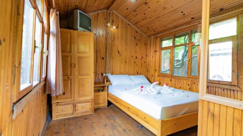 1 dormitorio con 1 cama en una habitación de madera en Turkmen Tree Houses, en Olympos