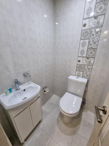 a white bathroom with a toilet and a sink at Anga Yerevan Hotel in Yerevan