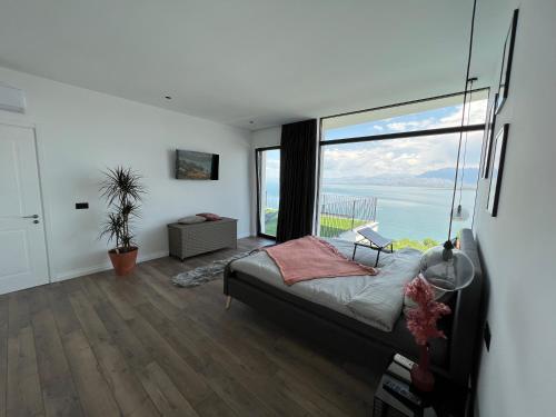 a bedroom with a bed and a large window at Lake Breeze Villa with a Pool & Magnificent Views in Široka