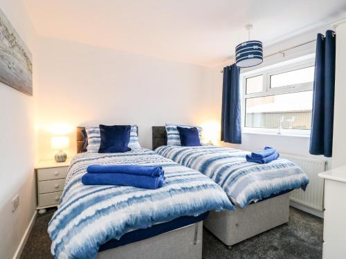 two beds in a bedroom with blue pillows on them at Rose Cottage in Skegness