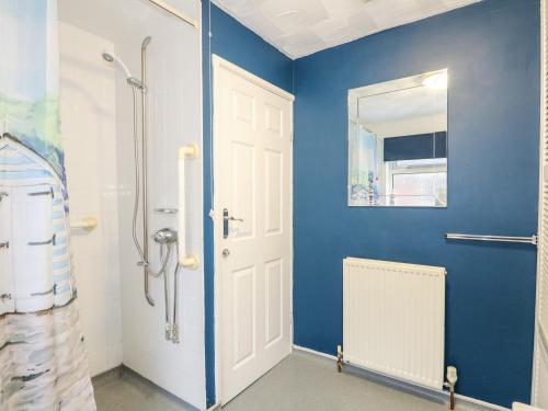 ein Bad mit einer Dusche und einer blauen Wand in der Unterkunft Rose Cottage in Skegness