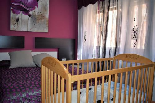 a crib in a bedroom with a pink wall at Dinoapartamento in Teruel