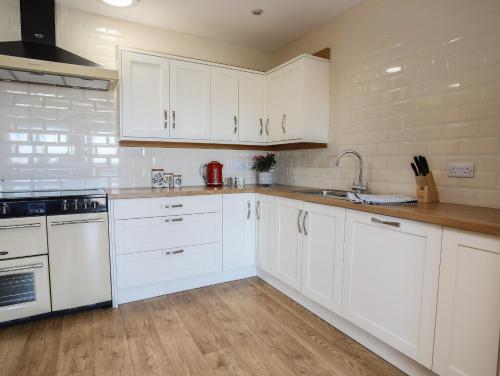 a white kitchen with white cabinets and a sink at The Elberry in Llanfairpwllgwyngyll