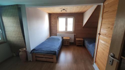 Habitación pequeña con 2 camas y ventana en Dom z basenem nad Narwia, en Szablak