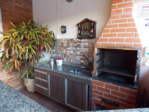 a kitchen with a brick fireplace and a sink at Cantinho rústico com piscina privativa em Brotas SP in Brotas