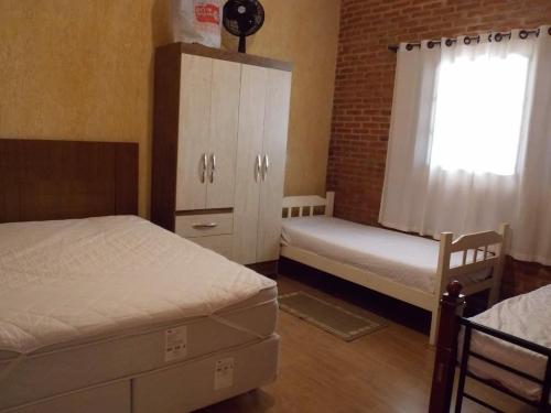 a bedroom with two beds and a cabinet and a window at Cantinho rústico com piscina privativa em Brotas SP in Brotas