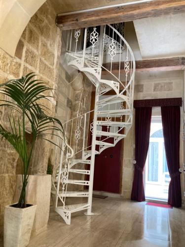 a white spiral staircase in a room with a plant at Ta' Marta Lodge in Victoria
