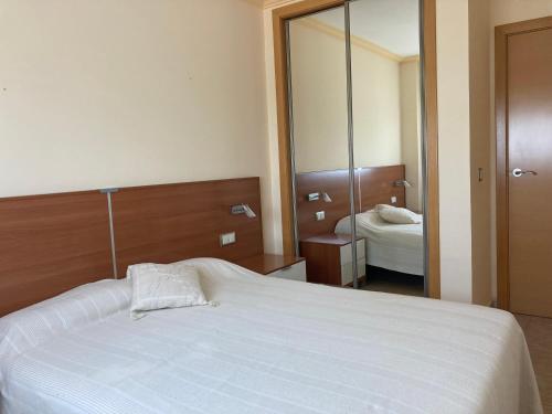 una camera con letto bianco e specchio di Apartamento playa Valencia, Mareny Blau a El Mareny Blau