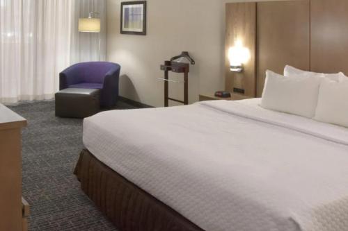 a hotel room with a large bed and a chair at Crowne Plaza Cleveland Airport by IHG in Middleburg Heights