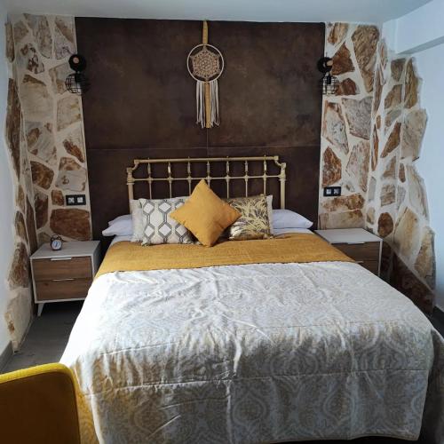 um quarto com uma cama grande com lençóis e almofadas douradas em La Medina Alta em Setenil de las Bodegas