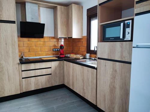 uma cozinha com armários de madeira, um micro-ondas e um frigorífico em La Medina Alta em Setenil de las Bodegas