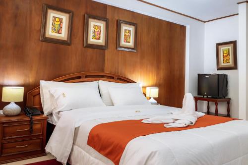 a bedroom with a bed with white sheets and a tv at Recreo Hotel in Trujillo