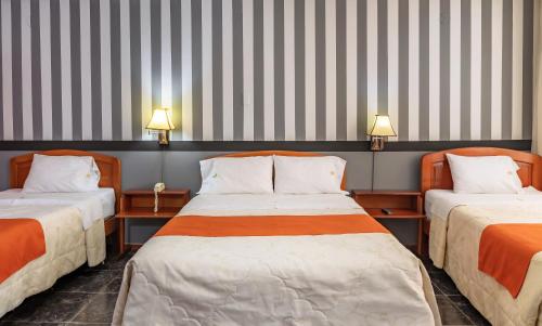 two beds in a room with striped walls at Recreo Hotel in Trujillo