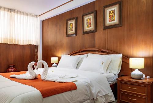 two swans sitting on a bed in a hotel room at Recreo Hotel in Trujillo
