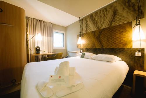 a hotel room with a large white bed with a sign on it at ibis Avignon Centre Gare in Avignon