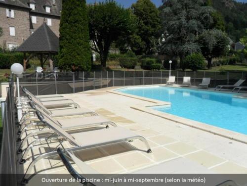 a row of lounge chairs next to a swimming pool at Hotel Beauséjour in Vic-sur-Cère