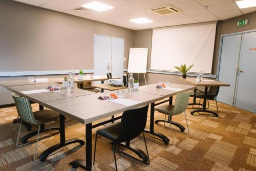 a conference room with tables and chairs and a whiteboard at ibis Avignon Centre Gare in Avignon