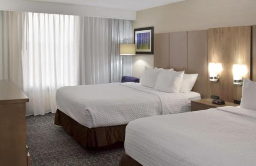 a hotel room with two beds with white sheets at Crowne Plaza Cleveland Airport by IHG in Middleburg Heights