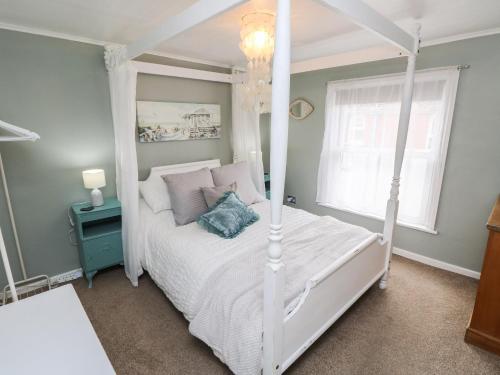 a bedroom with a white canopy bed with a blue pillow at Linda Cottage in Ryde