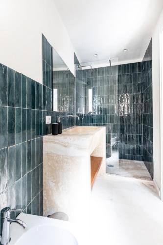 a bathroom with green tiled walls and a sink at LE CASE DEL FICO D'INDIA FAVIGNANA in Favignana