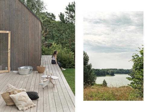 a woman sitting on a deck with a view of a lake at domki w lesie Gdańsk 35 km in Bożepole Królewskie