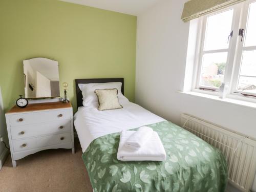 a bedroom with a bed and a dresser and a mirror at Rosemead in Moreton in Marsh