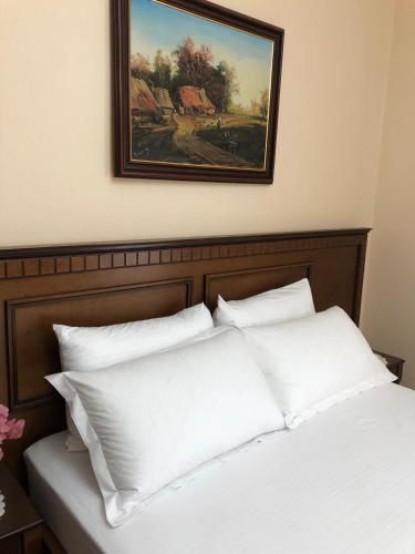 a bed with white pillows and a painting on the wall at Villa Garden in Berat