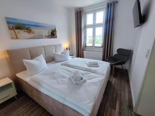 a bedroom with a bed with white sheets and a window at Villa Boberg Apartments in Ostseebad Koserow