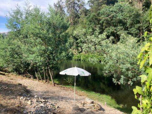 an umbrella sitting in the sand next to a river at Quinta de Varzielas - Agroturismo in Castelo de Paiva