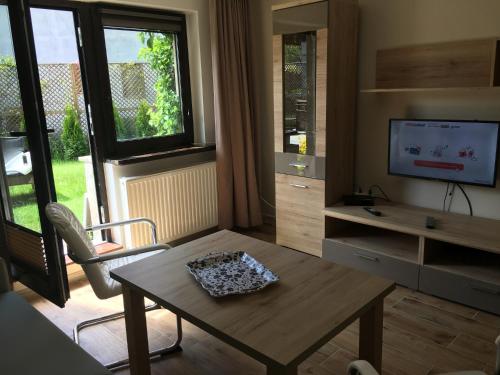 ein Wohnzimmer mit einem Tisch und einem TV in der Unterkunft BALTIC VIBES APARTAMENT in Kołobrzeg