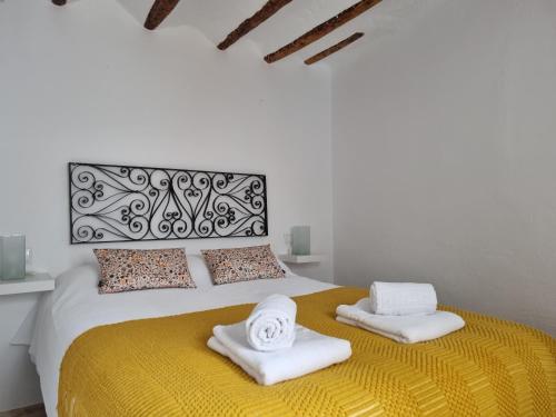 Un dormitorio blanco con una cama amarilla con toallas. en CASITA CAZORLA, en Cazorla